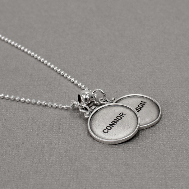 vintage style sterling silver circles with raised edges, hand stamped with names , shown from the side