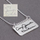 Side view of silver rectangle jewelry engraved with handwritten signature, shown with original handwriting, on gray
