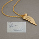 gold angel wing with handwriting, shown with original handwritten note used to personalize it