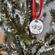 Hand stamped double heart ornament, shown hanging on a tree. Ornament is made with fine pewter, hung on a red ribbon, with 2 raised hearts, and the year stamped on the bottom.