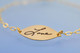 Gold Signature Bracelet, shown from the side with the handwritten word Love