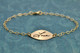 Sweet Petal Gold Handwriting Bracelet, shown from side on green