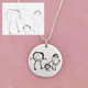 Child's drawing of Mom, Dad & her, engraved on a 7/8" a custom silver disc necklace, shown with original artwork used to personalize it