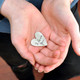 Personalized heart pocket token with handwriting, held in hands, with writing side up