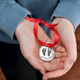 Custom fine pewter memorial Christmas ornament, personalized with your child's footprints or handprints, shown in model's hands