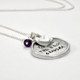 Side view of custom silver circle handwriting necklace, with a birthstone & heart charm, personalized with grandson's actual handwriting