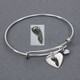 Side view of custom adjustable silver charm bracelet with silver heart charm with child's actual footprint engraved on it, shown with the original footprint used to personalize it, along with a puffed silver heart charm.