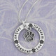 Silver circle necklace with pets names around the edge, and a silver paw charm hanging within the circle, all on a silver chain (top view)