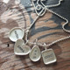 Sterling silver hand stamped mother's necklace with raised edge charms, shown close up on wood