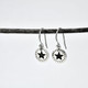 Handmade sterling silver star earrings with dotted border on sterling silver ear wires, shown shown hanging from a twig