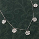 Custom silver hand stamped disc necklace for mom, personalized with kids' names on each disc, shown on green