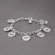 Side view of hand stamped sterling silver custom bracelet for Grandma, stamped with 6 kids' names on circle charms, with a silver puffed heart charm