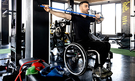 A man in a wheelchair is working out in a gym - image