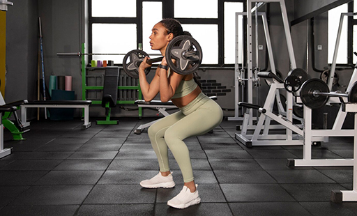 A woman squatting down with a barbell - image