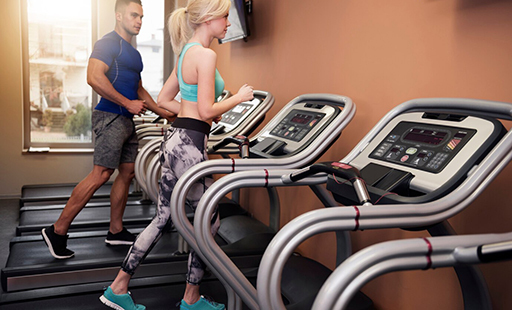 A gym with treadmills and exercise machines lined up in a row - image