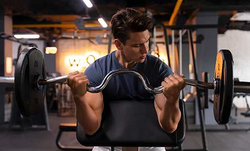 A man lifts a barbell over his head in a gym - image