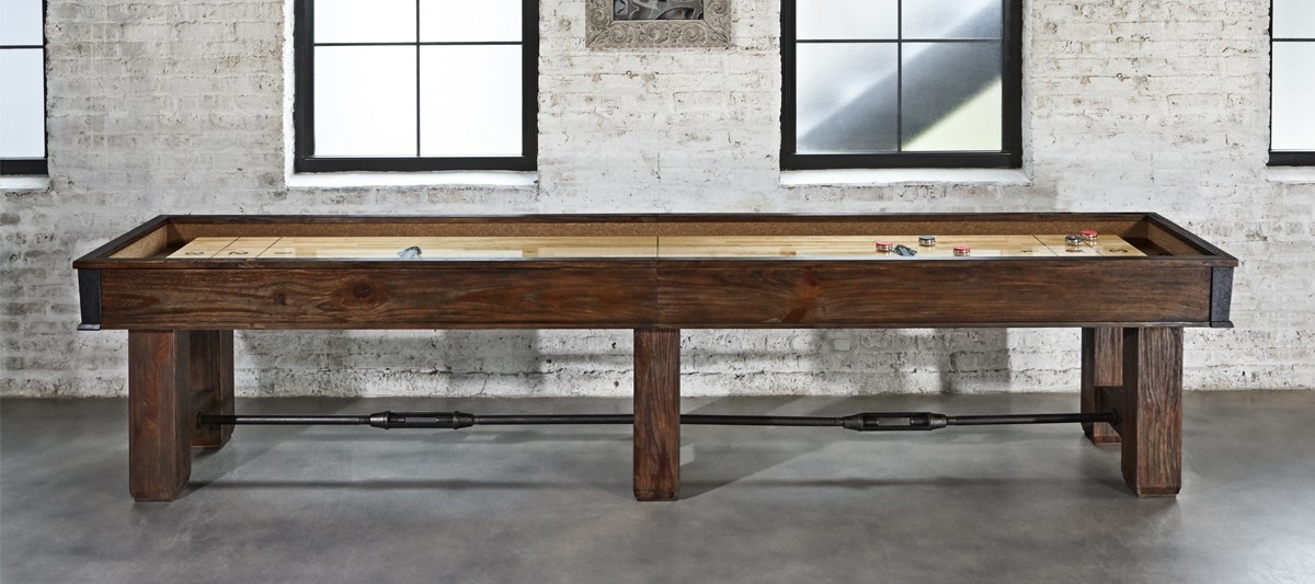 A wooden shuffleboard table in front of a brick wall - image