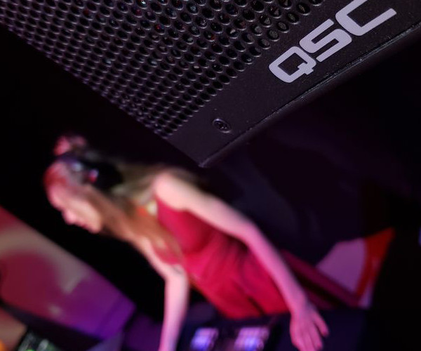 A QSC Speaker on a sharp angle. Blurred red background.