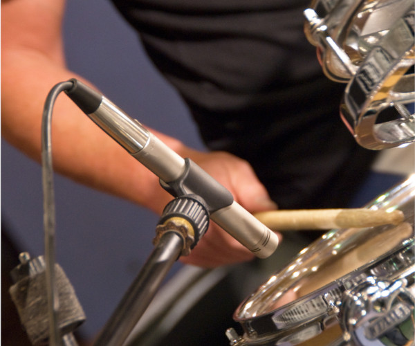 A microphone records a drum kit up close.