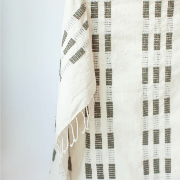 Close-up of a stone-colored hand towel with decorative tassels, adding a touch of texture and style to a bathroom setting.