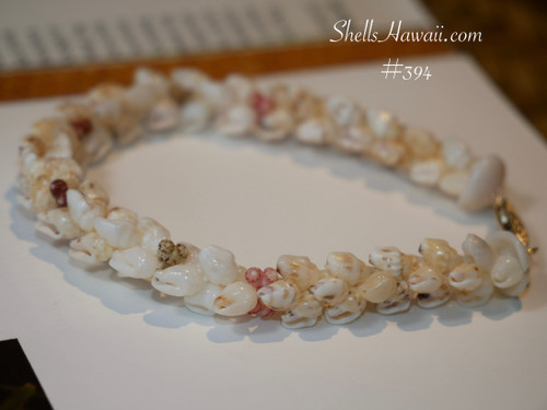 Hawaiian shell bracelet side view showing off white momi shells and natural kahelelani shells in pink green and red burgundy tones