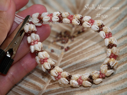 Close up ombre style Kipona shell bracelet shown on hand before adding clasp, featuring genuine yellow Lenalena and off white Momi shells with pink flower, brown, black, and burgundy Kahelelani shell accents. Photo highlights the quality of the shells, detailed workmanship, and balanced flow of shell colors and shell sizes throughout the bracelet.