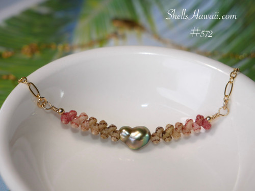 Close up ombre Kahelelani shell necklace with clasp softly shown in background featuring green, Keʻokeʻo, and pink flower Niihau shells paired with a green bronze Keshi-style pearl on a fancy Italian 14k gold filled chain. Niihau shell necklace gift under $200, Hawaiian shell necklace gift under $200, ニイハウ ミニマリスト ネックレス.