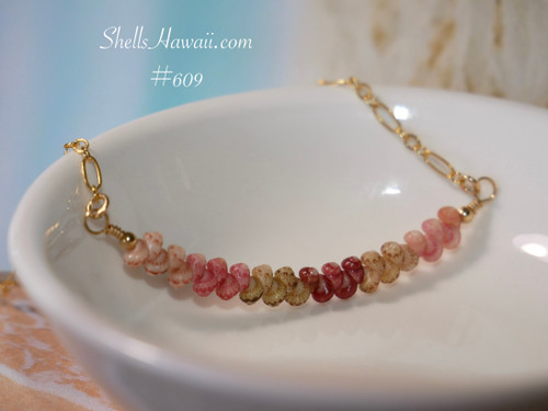 Genuine Kahelelani shell necklace from Niʻihau shown beside a coin for size reference featuring ombré Keʻokeʻo, pink flower, green, red burgundy, and soft pink shell colors in a handcrafted floating design.