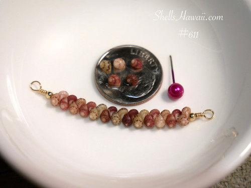 Handcrafted curved floating shell necklace from Hawaiʻi displayed beside a coin for size reference featuring Keʻokeʻo, Niʻihau green, and Kauaʻi burgundy Kahelelani shells.