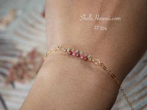 bl_704
Tropical Kahelelani shell bracelet worn on wrist featuring genuine Niʻihau shells in soft pink flower, brown, and ʻōmaʻomaʻo green tones accented with delicate 14k gold filled chain. Elegant everyday Hawaiian shell jewelry with refined coastal style and island-inspired charm.