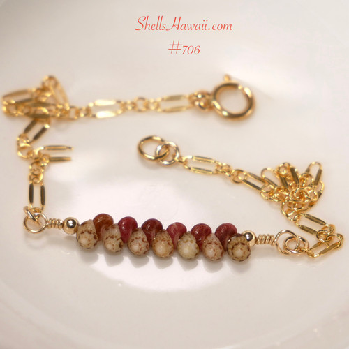 Authentic Niʻihau shell bracelet displayed on a white dish featuring genuine Kahelelani shells in ʻōmaʻomaʻo green and mākuʻe brown tones accented with delicate 14k gold filled chain. Elegant handcrafted Hawaiian shell jewelry with refined minimalist island style.