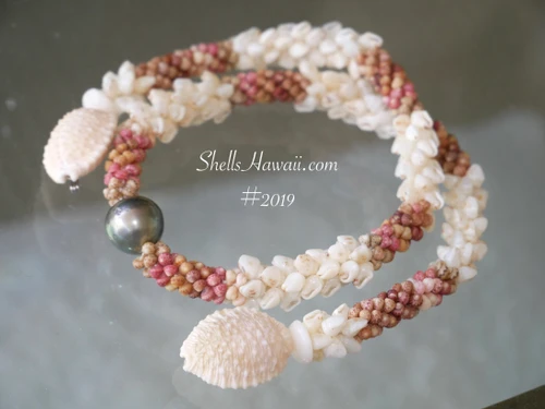 ninl_2019
Full display of a handmade Kipona Style Hawaiian shell necklace with Momi, Kahelelani, peacock Tahitian pearl, and creamy Granulated Cowrie shell clasp displayed on a tropical background.