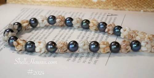 Close-up detail of Niʻihau Momi shells in Crown Flower style paired with lustrous dark Edison pearls in a Hawaiian shell lei
