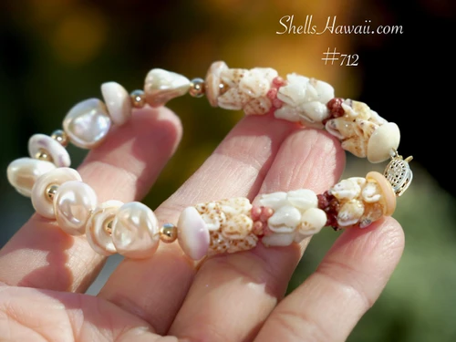 Hawaiian shell bracelet held in the hand for size comparison, showing lustrous Keshi pearls, Niʻihau Momi and Kahelelani shells, Puka shells, and gold-filled accents.