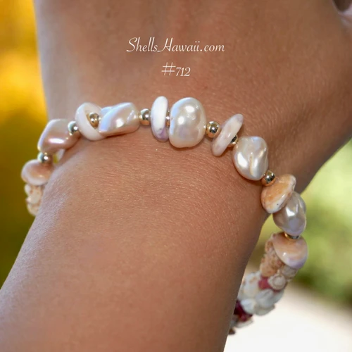 nibl_712
Close-up of lustrous Keshi pearls at the center of Hawaiian shell bracelet accented with 14K gold-filled beads and Puka shells in soft purple and brown tones.