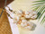 Close-up of Pineapple motif showing a body of Keʻokeʻo shells topped with yellow Lenalena Kahelelani; shells polished with natural sheen; 14K gold-filled hooks adding warmth.