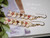 1⅝″ Heliconia Flower style Niʻihau earrings with off-white and soft yellow Momi shells, accented by pink flower, green, black, and brown Kahelelani shells. Evoking a lush tropical garden in bloom.