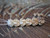 Handmade Hawaiian earrings displaying rich contrast among spotted Momi shells, combining natural color variety with traditional Crown Flower design. Light, elegant, and artisan-crafted.
