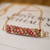 Close up poepoe design showing three strands of Kahelelani shells — pink ʻĀkala Pua, green ʻŌmaʻomaʻo, and white Keʻokeʻo — finished with 14K gold-filled chain.
