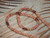 Beautiful 19" Kahelelani shell herringbone (Manoa Loa) style lei handcrafted with genuine Kauaʻi shells in natural brown, pink, green, and burgundy tones, finished with a puka shell clasp and matte texture.