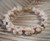 Detailed Niihau shell bracelet showing kahelelani shells in soft pink green red and brown with off white momi shells with red waha