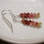 Kahelelani shell earrings lay flat showing burgundy pink and green shells in a straight minimalist drop, small Hawaiian shell earrings