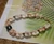 Close up clasp detail of Hawaiian shell bracelet showing 14k gold filled safety clasp with Momi shells and tiny Niihau Kahelelani shells in pink, red burgundy, green, and brown tones, handcrafted finish