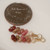 Colorful Kahelelani shell earrings from Kauai shown next to a coin for size comparison, mixed pink, green, brown and white tones, small Hawaiian shell earrings gift for her under $100