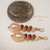 These dainty Hawaiian shell earrings are created with tiny size 10 Kahelelani shells from Niʻihau paired with soft peach freshwater pearls. The photo shows the earrings beside a US dime for size comparison, highlighting their lightweight organic island style and delicate handcrafted design. A beautiful affordable Niʻihau shell jewelry gift for her under $100.