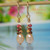 nier_3635
Dainty Niʻihau shell earrings featuring tiny colorful Kahelelani shells with peach freshwater pearls in a minimalist organic pattern drop style. The natural blend of black, yellow Kamoa, brown, green, pink, and off white Kamoa tones creates a soft island-inspired look perfect for everyday Hawaiian jewelry, gifting, or affordable authentic Hawaii shell jewelry.