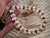 Close up ombre style Kipona shell bracelet shown on hand before adding clasp, featuring genuine yellow Lenalena and off white Momi shells with pink flower, brown, black, and burgundy Kahelelani shell accents. Photo highlights the quality of the shells, detailed workmanship, and balanced flow of shell colors and shell sizes throughout the bracelet.