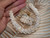 Overall matching Hawaiian shell necklace and earrings set in Crown Flower ombre design featuring light blue ʻŪliʻuli and off white Momi shells. Hand-held photo showing the size and detailed traditional Niʻihau shell jewelry craftsmanship.