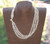 Authentic Hawaiian triple strand Niʻihau Momi shell lei necklace with off white Momi shells and traditional Puka shell clasp displayed on a neck mannequin showing the side clasp detail and layered shell arrangement.
