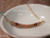 Authentic Hawaiian shell necklace from Niʻihau displayed in a white dish featuring a delicate curved arrangement of genuine Kahelelani shells with refined minimalist coastal style.